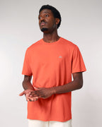 Man wearing an orange t-shirt with a small logo on a plain background