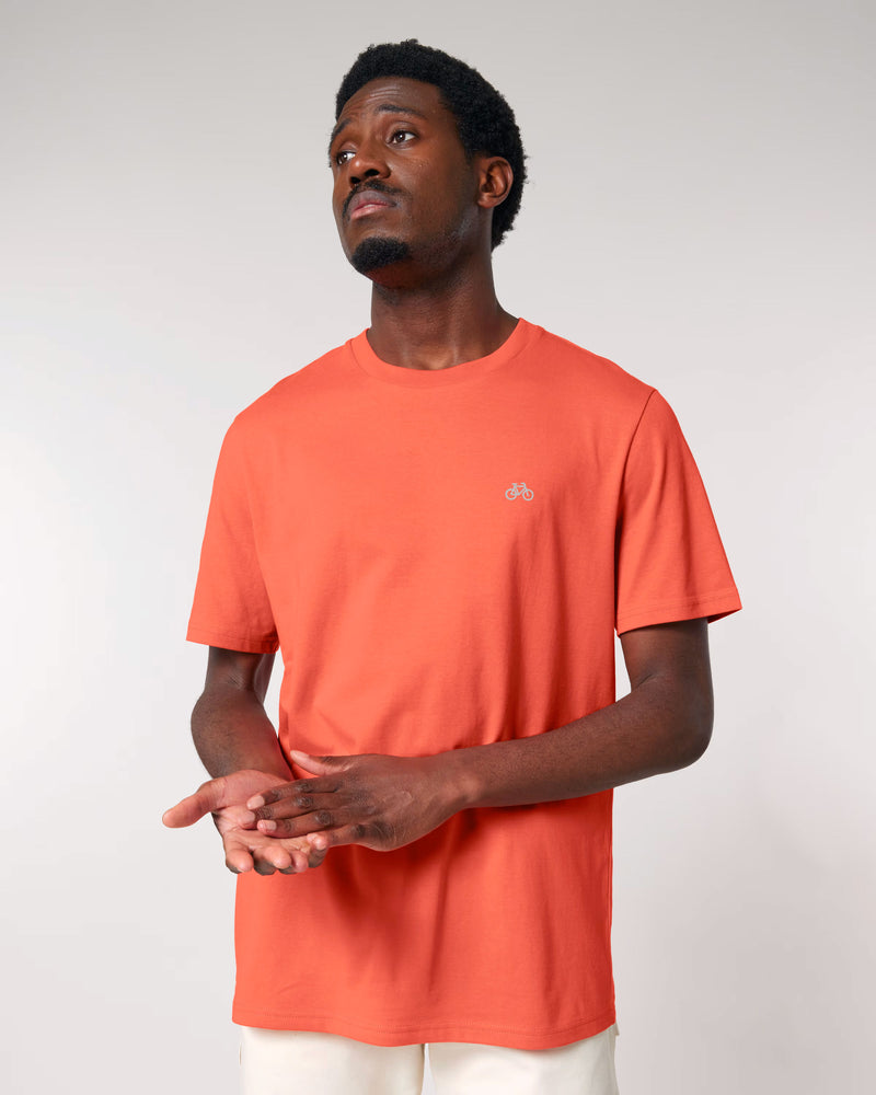 Man wearing an orange t-shirt with a small logo on a plain background