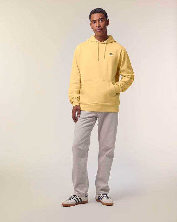 Man wearing a yellow hoodie and gray pants on a plain background